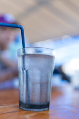 Clear glass of ice water with blue straw
