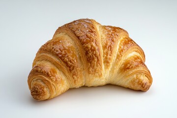 A freshly baked croissant resting on a white surface. The pastry has golden-brown flaky layers and is dusted with powdered sugar. It appears delicious and inviting for consumption.