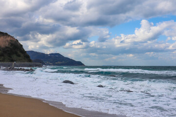 Dramatic Seascape with Crashing Waves and Cloudy Sky at Rocky Shore