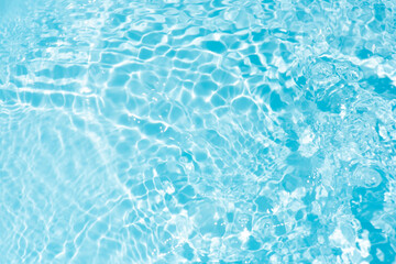 Blue water with ripples on the surface. Defocus blurred transparent blue colored clear calm water surface texture with splashes and bubbles. Water waves with shining pattern texture background.