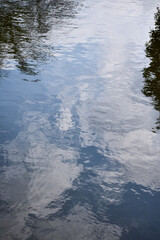 Close-up of the water with water reflection of clouds of the pool in a public park. Clear water with sky and clouds reflection. Water reflection. Nature scene.
