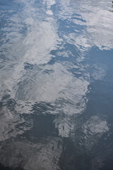 Close-up of the water with water reflection of clouds of the pool in a public park. Clear water with sky and clouds reflection. Water reflection. Nature scene.