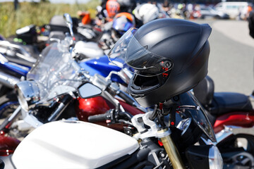 Closeup black moto helmet on motorcycle handlebars against blurred background