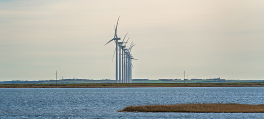 Fototapeta premium Wind Turbines Majestically Standing Tall Over the Serene and Peaceful Waters Nearby