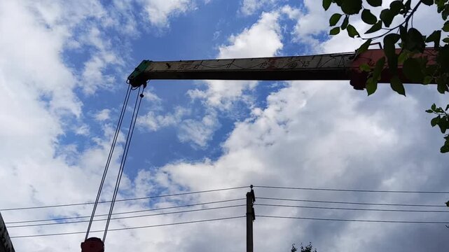 A crane operator controls the extension of a telescopic boom, pushing the crane arm forward during a construction task. Captured in an industrial setting, this scene is ideal for topics