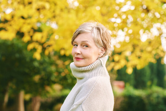 Close up portrait of happy mature 55 - 60 year old woman posing in autumn park, active and healthy lifestyle
