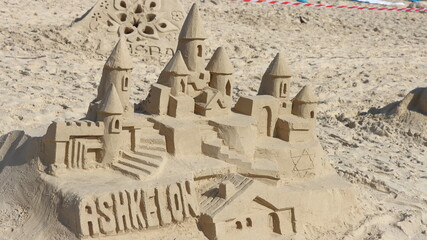 Sandcastle on the beach with umbrella and blue sky in the background,Ashqelon,Israel.