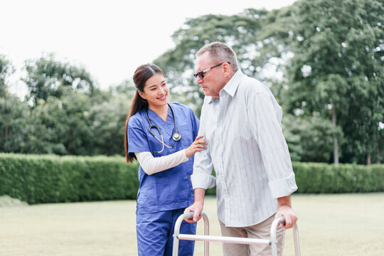 Home caregiver supports elderly man with walker outdoors, providing compassionate assistance and encouragement in peaceful garden setting, fostering trust and well being