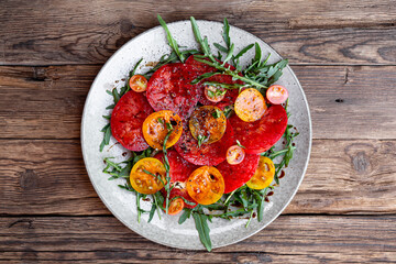 Simple Italian Salad with Tomatoes and Arugula on old wooden background, Italian Food
