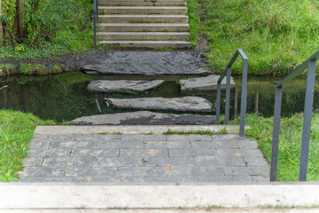 Stepping Stones in a Stream. A narrow path made of stone slabs leads over a shallow stream. The...