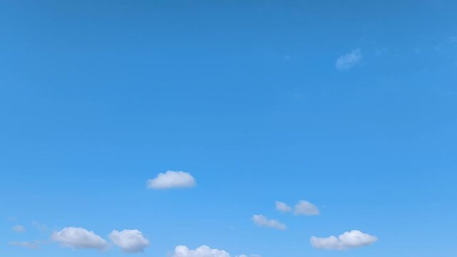 Filming of white clouds moving across the blue sky