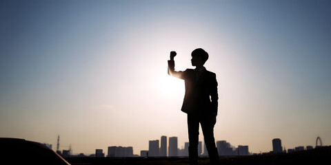 Silhouette of Triumph: A silhouette of an empowered individual stands tall against a radiant sky, fist raised in a gesture of triumph. It is a symbol of personal victory. 