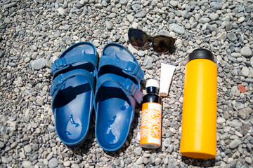 A close-up photo of a pair of summer slippers gently resting on golden beach sand, with soft sea...