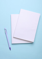 Magazines, sketchbooks or notebooks with white blank covers on blue background. Mockup for design