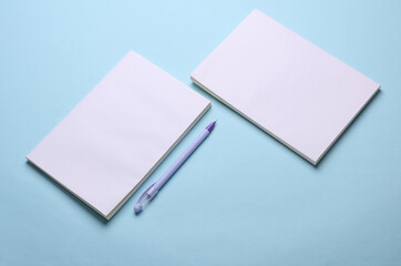 Magazines, sketchbooks or notebooks with white blank covers on blue background. Mockup for design