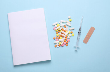 Blank medical journal or notebook with white cover and medicines on blue background. Mockup for design © splitov27