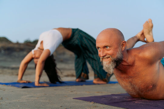 Couple Enjoying Yoga Poses on the Beach at Sunset
