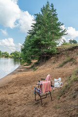 Folding chairs with towels, bags, a mat on a wild sandy beach
