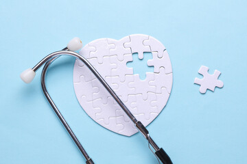 Stethoscope and white puzzle in the shape of a heart. Diagnosis and treatment of heart diseases. Mockup for design
