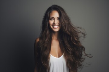 Naklejka premium Studio portrait of smiling woman with long, healthy brown hair blowing in wind