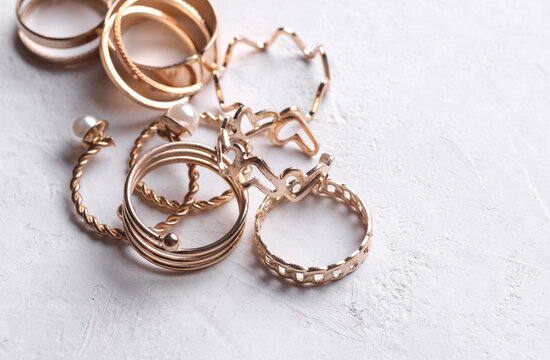 Many Gold rings of different shapes on a white concrete background. Jewelry store, beauty concept