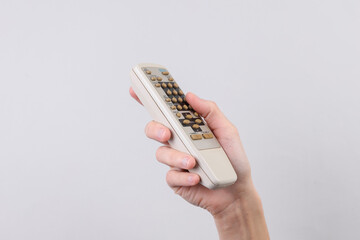 Female hand holding retro tv remote control on grey background