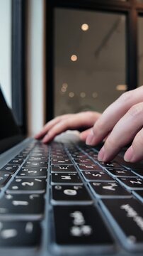 Close-up vertical view of hand typing on laptop at coffee shop on holidays. Concept of working outdoors for relaxation, holiday workspace, and inspiration creativity in working.