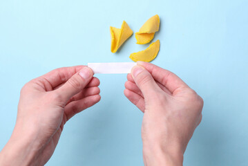 Hand holding empty white piece of paper to message or telling, blank inside for prediction words Fortune cookie on blue background