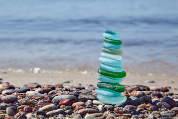 pyramid of balancing glass stones on the seashore.