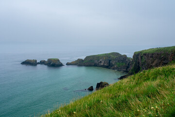 Cliffs, green and blue water on Coast of Atlantic Ocean. Carrick a Rede Rope Bridge, Ballintoy, Northern Ireland. Beautiful Landscape and rock formation