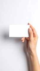Obraz premium A hand holds a blank white card against a white background