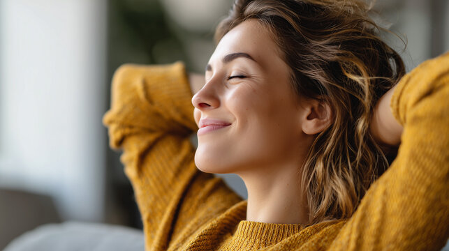 A young woman in a yellow sweater relaxes with her hands behind her head, smiling peacefully with her eyes closed. - Powered by Adobe