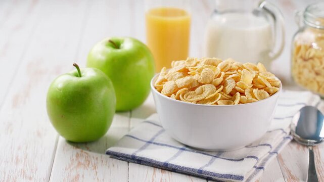Breakfast for kids with corn flakes and and fruits and juice on a light kitchen table. Healthy corn flakes and milk for breakfast with fruit.