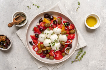 Fresh salad featuring creamy mozzarella balls, vibrant cherry tomatoes, assorted olives, and herbs, elegantly arranged on a rustic plate, showcasing healthy eating and culinary artistry