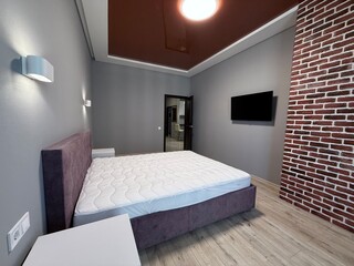 Modern bedroom with exposed brick wall and mounted TV