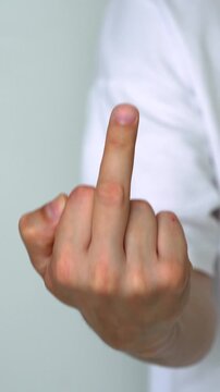 Adult man showing middle finger close-up on white background.
Violence, negativity, aggression, gesticulation