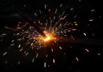 Close up of bright orange sparks flying from a welding torch at night fire heat