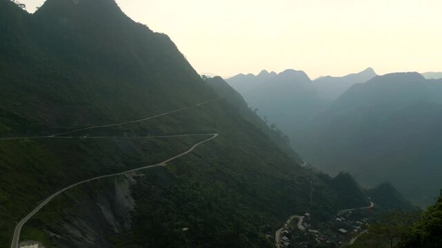 Drone view of winding mountain road in Ha Giang next to a deep valley during the Ha Giang Loop with Mystic weather. 