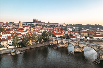 Obraz premium Bright colors fill the sky as the sun rises over Prague, illuminating the Vltava River and its medieval architecture.