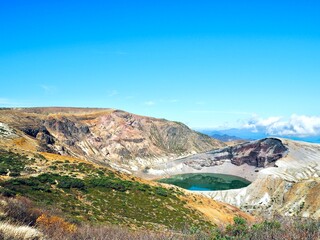 Fototapeta premium A breathtaking volcanic crater lake Okama on Mount Zao surrounded by rugged mountains.