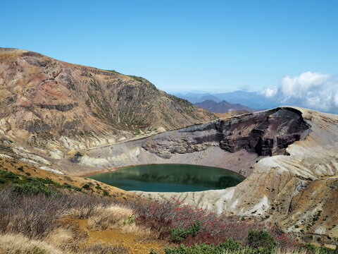 Volcanic terrain of Mount Zao with the famous Okama Crater Lake with clear blue sky.