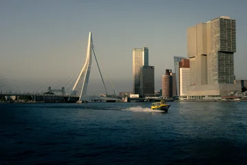Gordijnen Rotterdam Rotterdam's Erasmus Bridge with skyscrapers at dusk, with a yellow water taxi on the New Meuse  © Matt A. Hawk