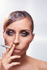 Fototapeta premium Close-Up Portrait of a Woman Smoking a Cigarette and Exhaling Smoke