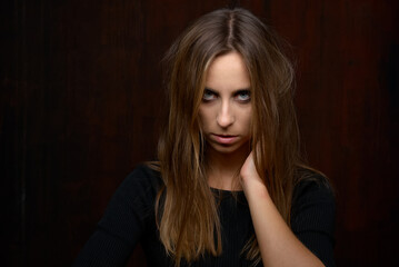 Fototapeta premium Pensive Woman in Dark Clothing Against Wooden Background