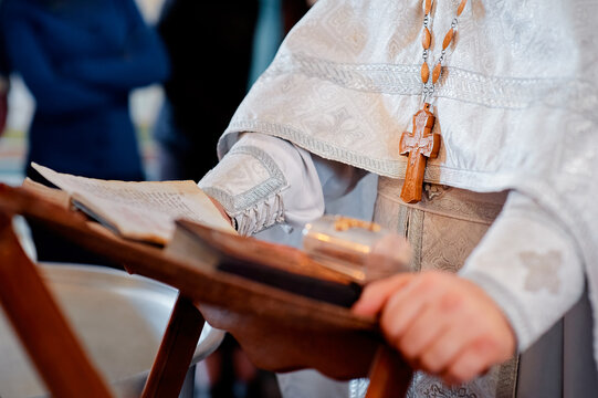 An orthodox priest wearing ceremonial robes and holding a sacred book, shown during a ritual service, symbolizing faith, tradition, and religious observance.