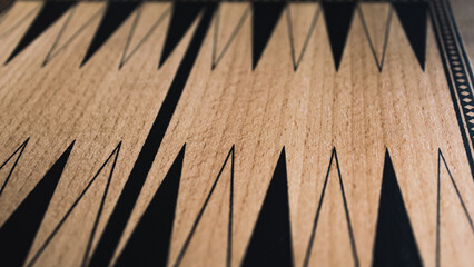 a close-up view of a wooden backgammon board with pips arranged in an alternating pattern with copy space. abstract background or wide banner