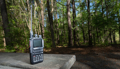 Portable two-way radio on a picnic bench in a thick forest