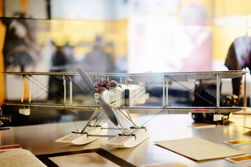 A vintage biplane model displayed on a table with blurred background. © luengo_ua