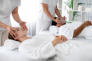 Obraz premium Serene modern daylight ambiance of spa salon, couple customer indulges in rejuvenating with facial skincare mask. Facial skin treatment and beauty cosmetology procedure for face. Quiescent