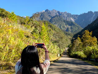 Woman taking photo of Mt. Kinabalu in Mesilau Kundasang Ranau Sabah Malaysia